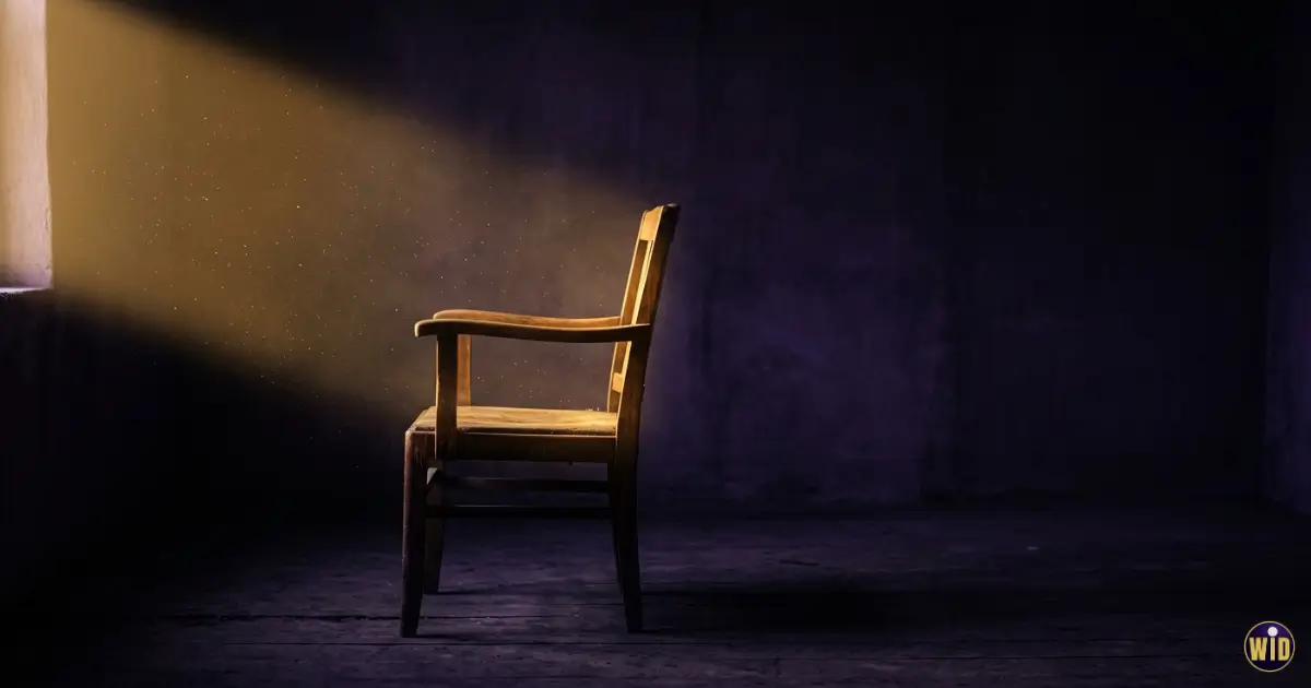 An empty chair in a dark room lit by a shaft of gold light, illustrating dreaming of death